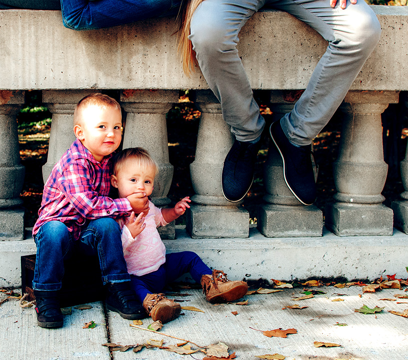 Parents hanging out on a wall ledge while their children are cuddling below them.