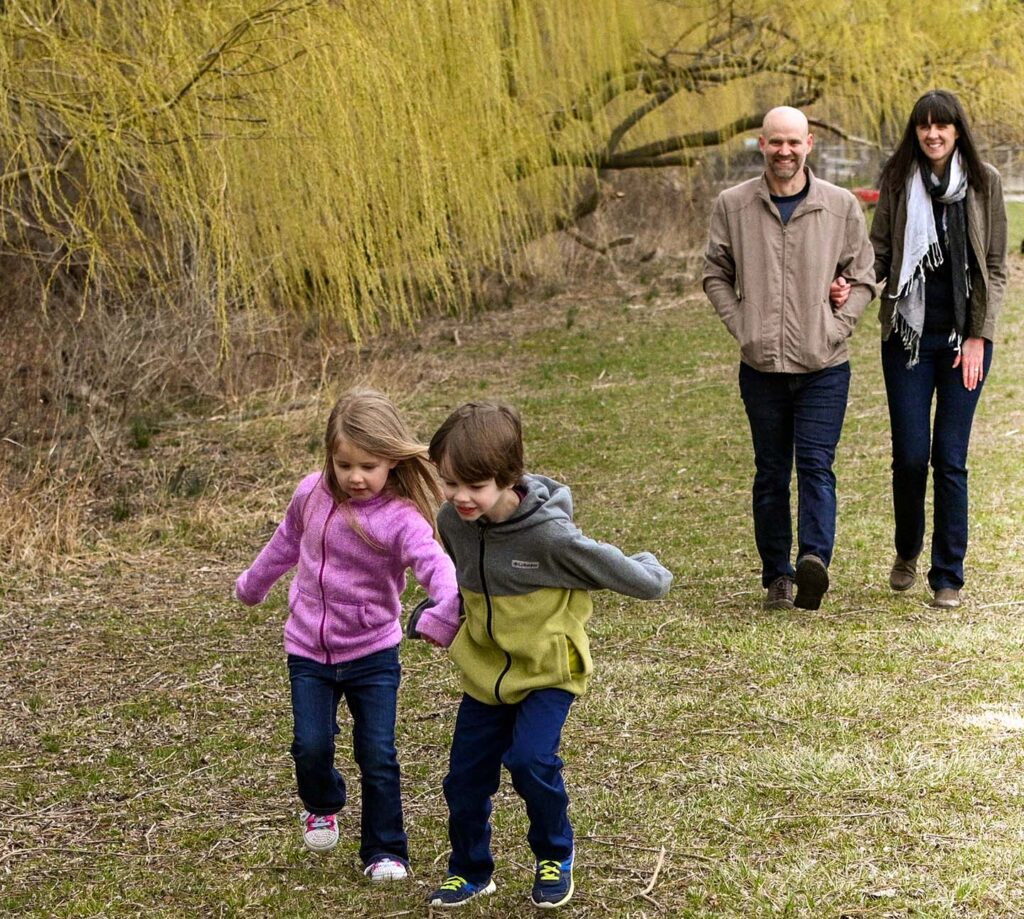 Photograph of two children running while parents are walking behind them.