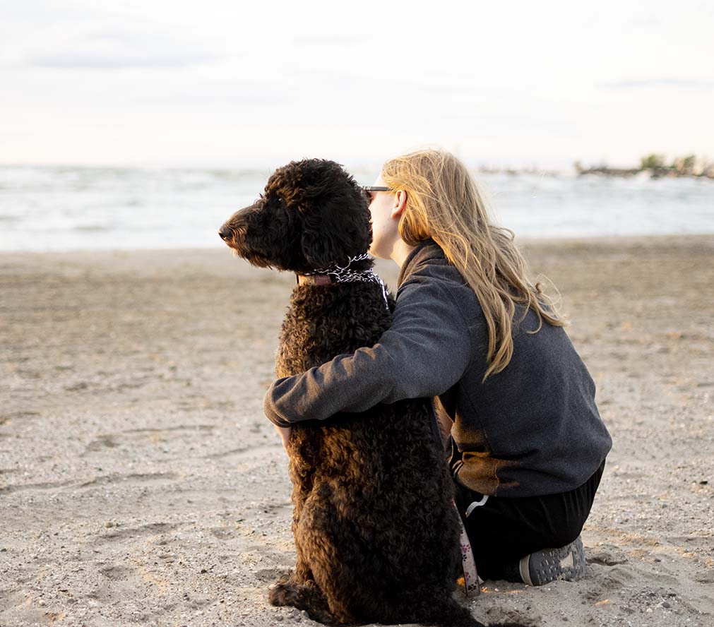 A girl and her dog watching the sunset at the beach, showing a smaller aperture.