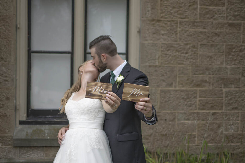 Wedding photos of the couple kissing and holding a Mrs & Mr sign.