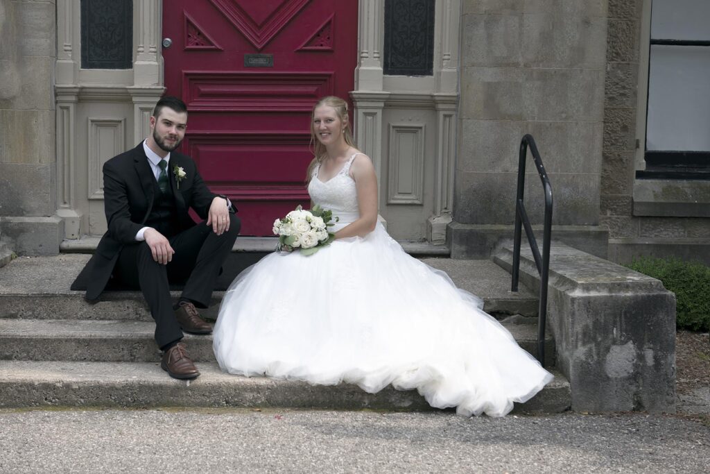 Bride and groom on the front steps of a building.